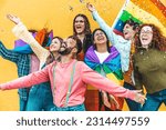 Diverse group of young people celebrating gay pride festival throwing confetti in the air - Lgbt community concept with guys and girls hugging together outdoors
