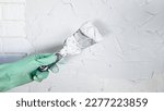 Small photo of The hand of a worker holding a spatula for applying putty to the walls