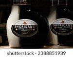 Small photo of Bottles of Irish Sheridan's coffee layered liqueur on blurred background of in wooden box. Ukraine, Zhytomyr, November, 15, 2023