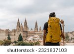 Small photo of Camino de Santiago - Young hipster pilgrim ends the Way of St James pilgrimage enjoying cathedral and the Santiago de Compostela old town cityscape in Galicia, Spain