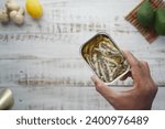 open tin of sardines on white tiles background.