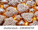 Christmas gingerbreads in the shapes of hearts and stars decorated with white icing, focus on the gingerbread cookie inside. Homemade, hand-decorated gingerbread cookies.