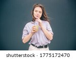 Young stylish trendy woman isolated over grey blue background. Dreamy girl drink cocktail or lemonade and enjoy iw with closed eyes. Stand alone and poses. Tasty delicious drink.