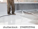 Small photo of A person using high-pressure equipment to clean the bottom of a water pool. Cleaning dirt. Before and after situation. Uniform and rubber boots.