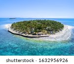 Surrounding Islands of Treasure Island, Fiji green lush tropical island in a blue and turquoise sea with islands in the background and clouds, drone aerial photo
