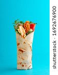 Small photo of Fresh chicken roll with fresh tomatos, salad, cheese and onions isolated on bright blue background. Side view.