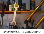 Small photo of A headset wrench hanging on a shelf in a cycloservice. Above the wrench itself there are various oils and next to it is a dismounted mountain bike fork. Bicycle maintenance concept.