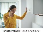 Small photo of Worried woman calling a boiler breakdown emergency service using her smartphone