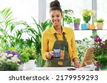 Smiling young florist holding a POS terminal and looking at camera, electronic payments concept