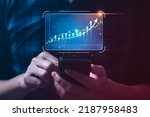 Businessman holding mobile and showing hologram graph and stock market statistics earn profit. business planning and strategy, forex trading analysis. Stock market, growth finance