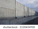 soundproof wall made of concrete porous ribbed material. fence of gray blocks embedded in metal beams, on street. road traffic noise  garden and residential area. protection of Jerusalem, rocket