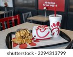 Small photo of Chick-fil-a food on the table in fast food restaurant. Chick fil a fries next to glass of cola and burger. Everett, WA, USA - April 2023