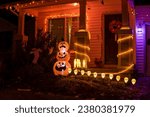 Glowing outdoor decorations with pumpkins, ghosts and orange garlands on the house porch