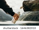 Small photo of Outdoor travel water bottle: a man's hand dials water from a water source into a bottle. Pure natural water.