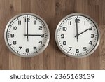 Small photo of Two clocks, one showing three o'clock, the other showing two o'clock. Time change symbol. Moving the hands backward in autumn to normal time.