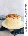 Small photo of Three tier hummingbird or carrot cake with cream cheese frosting and pecan nuts or walnuts on a white cake stand