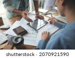 Small photo of Architects and interior designers women discussing to concept of building design. Estimation for construction project with tablet technology, Drawing, Material and Model. Selective focus center image