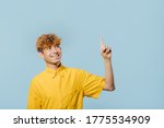Small photo of cheerful boy in yellow shirt pointing up direction on blue background, teenager cu coafura la moda, handsome guy in camasa galbena, tip tanar, nice teenager
