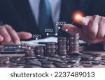 Small photo of Businessman touch arrow showing financial growth 2023 on stacked coins business background,Concepts savings money and accounting, investments, banks, bonds, dividends, inflation and digital assets.