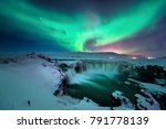A stunning glowing aurora shape like phoenix bird appears above the landscape of Godafoss waterfall in winter Iceland