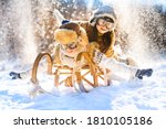 Two smiling children ride lying on a wooden retro sled on a sunny winter day. Active winter outdoors games. Happy Christmas vacation concept.