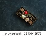 A set of beautiful sweets in a small box on a dark blue marble background. Overhead view, natural light. The concept of holidays, Valentine's Day