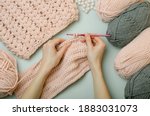 Crochet with your own hands.Knitting threads in pink and gray. Knitted scarf.Female hands hold a crochet hook and knit.DIY.Knitting rules. Creativity lessons.Winter activities during quarantine.