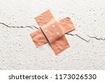 Small photo of band-aid plaster in cross shape on a crack in the wall, concept for botched construction and doctoring around symptoms, copy space