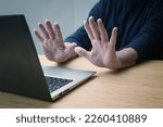 Small photo of Hands in defensive gesture against a laptop computer, avoiding further work on a hacked system or other danger and offence, online risk in business and privacy, copy space, selected focus