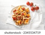 Baked puff pastry snacks with cream cheese, tomatoes and herb pesto, party finger food on a white plate, high angle view from above, copy space, selected focus