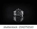 Small photo of Rolex wristwatch model cosmograph daytona oyster perpetual superlative chronometer with black ceramic bezel stainless steel body on black table with black wall background at authorized dealer shop