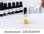 Small photo of chemical beaker , flask is on white table with blotting paper , fragrance bottle and essential oil bottle are used to blend the nice scent for making perfume and candle by perfumer in the laboratory