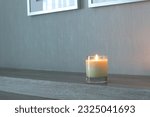  luxury aromatic scented candle glass is displayed on wooden table in the bedroom to create relax and romantic ambient on happy valentine day with background of nice wooden wall and phto frames