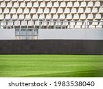 Empty stadium with white chairs in tribune and the green lawn grass