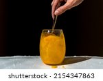Small photo of orange juice powder diluted in a glass of water, freshness, vitality concept, health, wellbeing