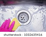 Close up sink drain and hand wearing pink rubber glove cleaning scrub steel sink with sponge. Housework concept