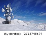 Radio aerial antenna mast with a lot of satellite dishes, parabolic reflector or dish antennas for microwave communications links on communication tower among snowy mountains