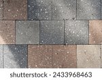 Neatly arranged section of pavement made of rectangular cobblestones. Material exhibiting variety of colors ranging from light beige to dark grey. Sharp edges