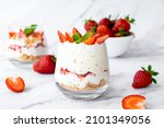 Strawberry dessert with white cocolate, whipped cream, granola and fresh strawberry in individual trifles glass on marble. Recipe of simple healthy homemade organic dessert, cheesecake, parfait.
