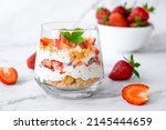 Small photo of Berry dessert in glass with fresh strawberry, biscuit and whipped cream. Vegan lactose free dessert with alternative milk of coconut. Recipe of healthy organic dessert, cheesecake or berry trifle cake
