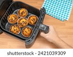 Small photo of HAND BAKING HOMEMADE MUFFINS OR CUPCAKES WITH CHOCOLATE CHIPS IN AIR FRYER AT THE KITCHEN. TOP VIEW.