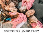 Small photo of happy family with triplet girls is lying in park, relaxing in the outdoors