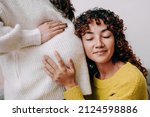 LGBT lesbian pregnant woman having tender moment listening her wife baby belly - Focus on right female