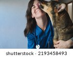 Happy stray dog licking vet woman doctor face inside private hospital - Focus on veterinarian