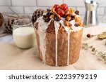 sweet bread for the Christmas holidays round and oval with dry fruits walnuts almonds cream icing cherries raisins on milk white countertop and decorated with dried flowers