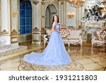 A young girl looks like a princess in a blue long dress. The image of Cinderella wearing a crown. The image of a young girl at the prom.