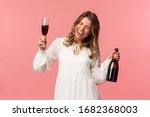 Holidays, spring and party concept. Portrait of excited and emotive good-looking blond girl dancing and celebrating, having fun saying yeah singing closed eyes, hold glass wine and bottle