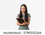 Pretty young asian female entrepreneur, small business owner fill in blank form for shipping, writing on clipboard, smiling enthusiastic as prepare list of order receivers, delivering to clients