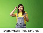 Small photo of Triumphing cute joyful asian girl hold smartphone, fist pump celebrating good news, read good news message, look telephone screen smiling happily, achieve success got persmission party