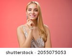 Small photo of Waist-up shot elegant good-looking wealthy young blond woman in brilliant accessorize silver glittering stylish dress touch chin have clever interesting idea smiling curiously, red background